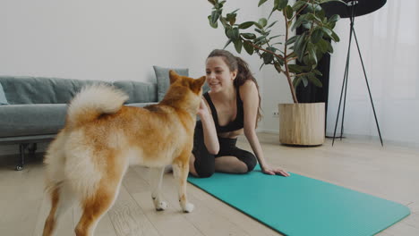 Ein-Mädchen-Macht-Eine-Pause-Von-Ihrer-Yogastunde,-Um-Ihren-Süßen-Hund-Zu-Füttern