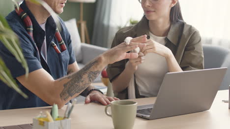 Pareja-Sosteniendo-Y-Acariciando-Una-Serpiente-Sentada-En-El-Escritorio-Frente-A-Una-Computadora-Portátil