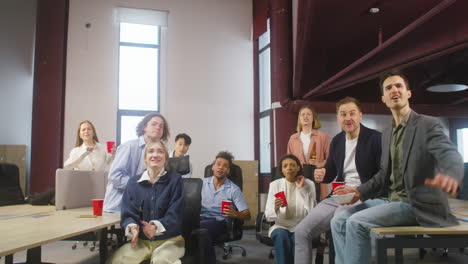 Grupo-De-Colegas-Multiétnicos-Viendo-Un-Partido-Deportivo,-Animando-Y-Apoyando-A-Su-Equipo-En-La-Oficina-1