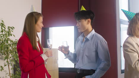 Man-And-Woman-Holding-Champagne-Glass-And-Talking-Together-At-The-Office-Party