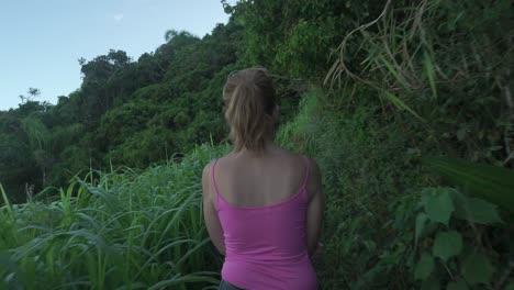 Tracking-follow-shot-of-young-girl-walking-on-mountain-forest