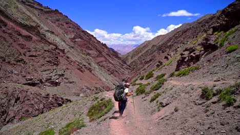 Toma-De-Seguimiento-Manual-De-Excursionistas-Caminando-Por-Un-Camino-Polvoriento-En-La-Ladera-De-Una-Montaña,-Durante-El-Día
