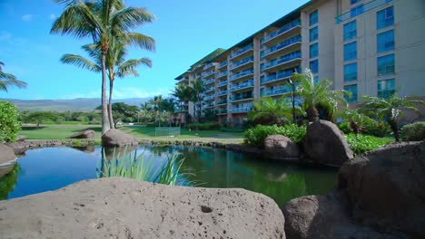 Paradise-holiday-resort-park-with-tropical-plants-and-ponds-with-natural-cliffs,-lush-vegetation-in-Hawaii