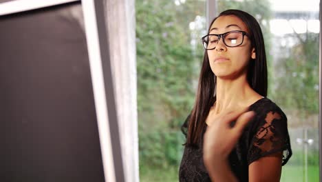 Young-beautiful-woman-with-black-hair-standing-in-front-of-the-mirror-and-touching-her-hair-at-home