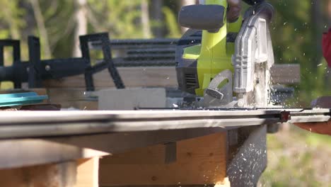 Slow-motion,-pan-shot,-of-a-circular-saw,-circling-through-a-plank,-on-a-sunny-summer-day,-in-Ostrobothnia,-Finland