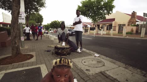 Ein-Männlicher-Straßenkünstler-In-Traditionellen-Südafrikanischen-Kostümen-Tanzt,-Während-Sein-Begleiter-Eine-Zulu-Trommel-Spielt