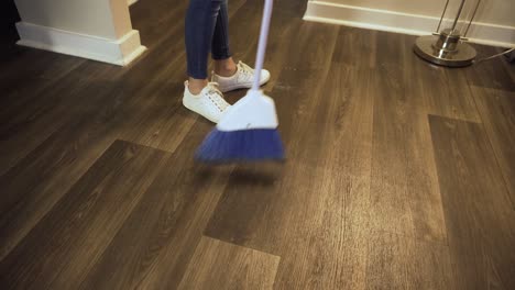 Young,-Latina-woman-casually-dressed-in-jeans-sweeps-clean-the-floors-of-her-apartment-home-during-the-quarantine