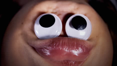 A-funny-ugly-duck-face,-made-by-putting-googly-eyes-on-the-chin-of-a-little-girl-and-shooting-upside-down