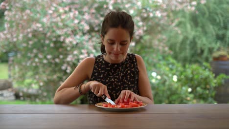 Young-Girl-Cutting-Red-Tomato-on-Wooden-Table-in-Backyard,-Bokeh-Background