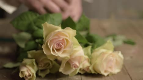 Florist-tying-ribbon-around-bunch-of-pink-and-white-pastel-roses