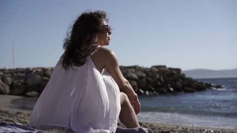 Young-women-sits-on-beach-and-takes-in-the-view-on-sandy-beach-in-Gibraltar,-Spain