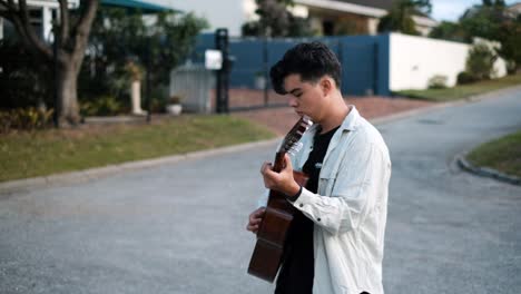 Toma-En-Cámara-Lenta-De-Un-Joven-Caminando-En-La-Calle-Mientras-Toca-Una-Guitarra-Acústica