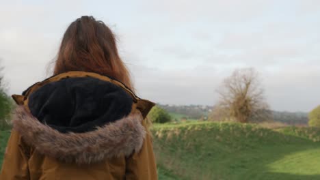 Young-woman-walks-across-path-between-fields-on-nature-trail