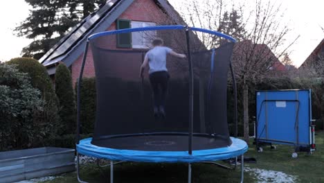 Un-Niño-Saltando-En-El-Trampolín-Y-Haciendo-Saltos-Mortales-En-El-Jardín