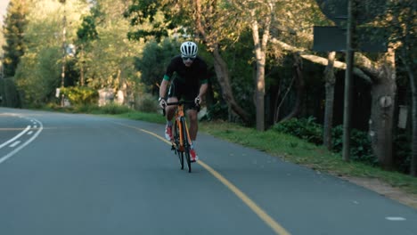 Tracking-Shot-of-a-Young-Male-Road-Cyclist-Racing-Up-a-Hill