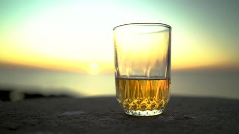 Nahaufnahme-Der-Hand-Des-Mannes,-Die-Bei-Sonnenuntergang-Ein-Bierglas-Am-Strand-Nimmt