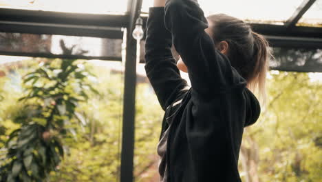 A-fit-young-woman-at-a-yoga-lesson,-raising-her-hands-while-doing-a-difficult-stretching-exercise