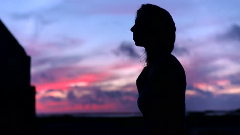 Woman-silhouette-with-colorful-pink-sunset-sky-and-blurry-background