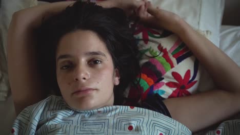 Portrait-of-young-girl-waking-up-on-bed,-closeup