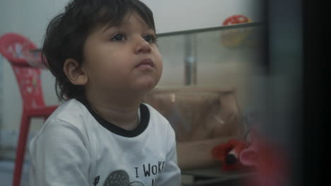 Baby-boy-with-brown-eyes-picking-his-nose-while-watching-TV