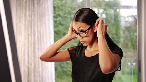 Young-brunette-woman-combing-her-hair-and-checking-her-appearance-in-front-of-the-mirror-at-home