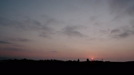 Static-shot-of-people-in-silhouette-admiring-the-sunset-on-Venice-beach,-California