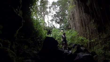 A-young-woman-carefully-descending-into-the-dark-tranquil-Kaumana-Caves,-Big-Island-of-Hawaii