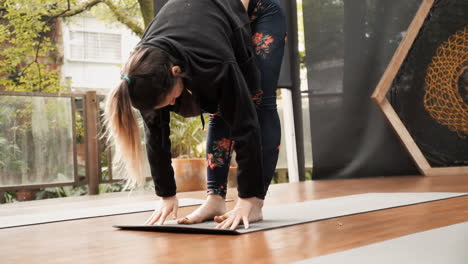 A-fit-young-woman-at-a-yoga-lesson,-doing-stretching-exercises-with-her-full-body:-feet,-legs,-arms-and-hands-cooperate-to-awaken-and-strengthen-the-muscles