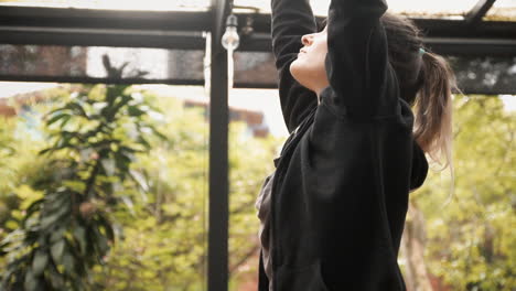 Slow-motion-handheld-shot:-a-fit-young-woman-at-a-yoga-lesson,-raising-her-hands-in-the-air,-then-going-down-while-stretching-her-muscles