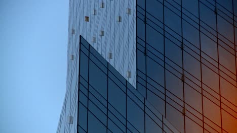 Moderne-Architektur-Aus-Nächster-Nähe-Mit-Verspiegelten-Glaswänden,-Die-Einen-Riesigen-Orangefarbenen-Ball-Der-Untergehenden-Sonne-Reflektieren