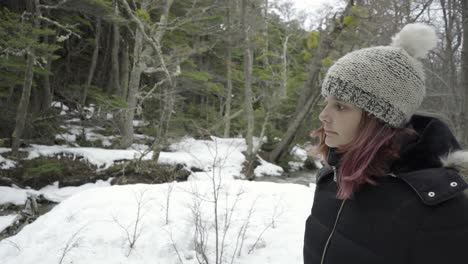 Portrait-in-profile-of-worried-girl-with-pink-hair-and-white-beanie-in-snowy-forest