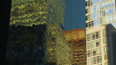 Vista-De-Cerca-Reflejo-De-Los-Edificios-Cercanos-Y-El-Cielo-Azul-En-El-Exterior-Del-Espejo-Del-Rascacielos-Moderno-En-La-Ciudad-De-Nueva-York-Cerca-De-Times-Square