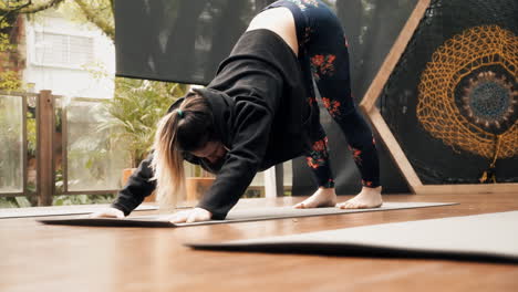 A-yoga-student,-in-a-classroom,-practising-an-exercise-to-flex-and-stretch-her-back-and-shoulder-muscles