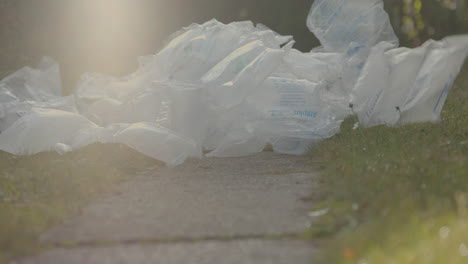 Extreme-low-angle-shot-of-packaging-waste-falling-onto-ground-in-garden---nature