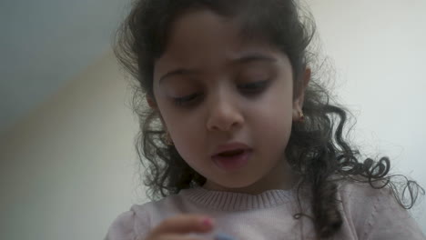 Little-girl-with-long-curly-brown-hair-busy-playing-with-her-toy-doll