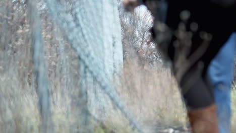 A-woman-stealthily-entering-a-private-property-by-entering-from-a-hole-in-a-fence