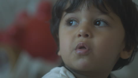 Little-boy-toddler-with-brown-eyes-and-brown-hair-chewing-his-food-and-looking-up-close-up-portrait