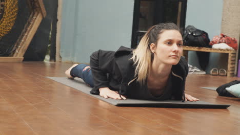 A-concentrated-yoga-student-in-a-classroom,-completing-an-exercise-of-her-lesson:-raising-her-head-and-lowering-it,-stretching-the-shoulder-and-neck-muscles