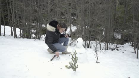 Chica-Con-Cabello-Rosado-Hace-Un-Muñeco-De-Nieve-En-El-Bosque-De-Invierno