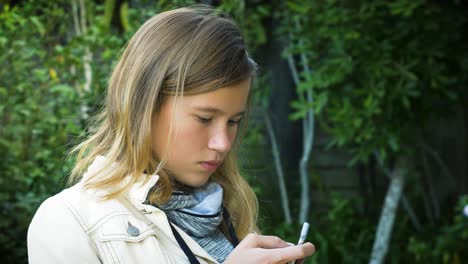 Ein-Attraktives-Teenager-Mädchen-überprüft-Social-Media-Nachrichten-Auf-Ihrem-Smartphone-Im-Garten