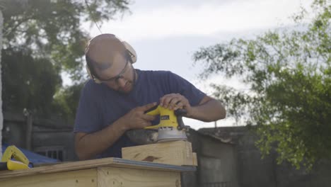 Carpintero-Utiliza-Una-Herramienta-Eléctrica-Lijadora-Orbital-Para-Lijar-Un-Trozo-De-Madera