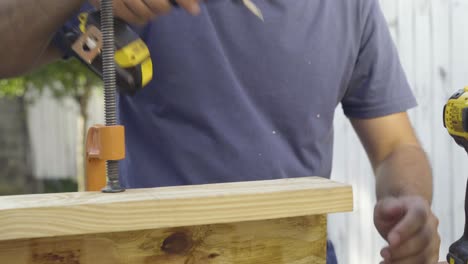 Close-up-shot-of-carpenter-woodworker-using-power-tools-to-screw-2x4-planks-and-plywood-board-together