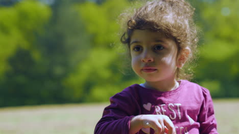 Little-girl-eating-food-during-a-summer-picnic-outdoors