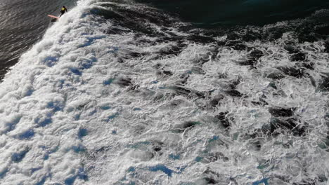 Surfer-Zander-Adelsohn-rides-morning-wave-on-longboard-w--aerial-4k-drone-following-from-above-at-Huntington-Beach-pier-surfing-competition-wearing-yellow-wetsuit-rash-guard-in-Pacific-Ocean