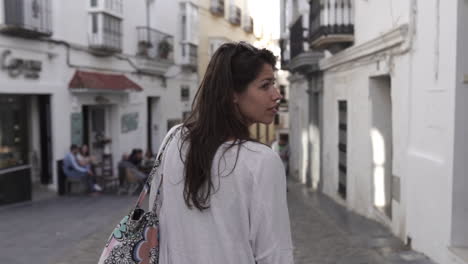 Young-women-walks-down-shopping-street-in-Gibraltar,-Spain,-looking-around-at-shops