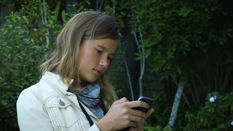 Ein-Attraktives-Teenager-Mädchen-überprüft-Social-Media-Nachrichten-Auf-Ihrem-Smartphone-Im-Garten-1