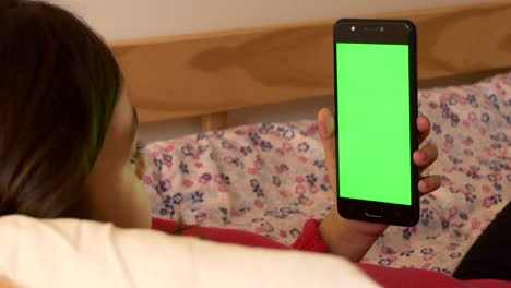 A-tired-young-girl-rubs-her-eyes-while-using-a-green-screen-cell-phone