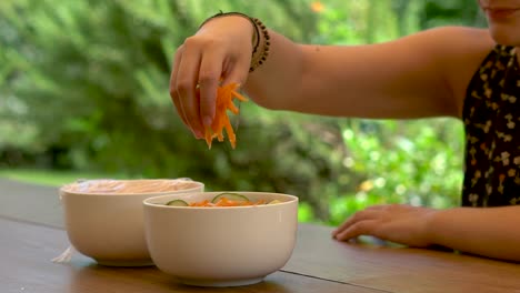 Closeup-of-Hand-of-Woman-Adding-Grated-Carrots-In-Bowl,-Slow-Motion