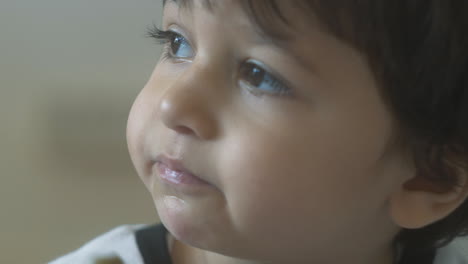 Close-up-young-boy-with-brown-eyes-eating-olives-off-his-fingertip