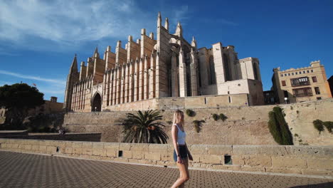 Girl-is-walking-in-front-of-the-Catedral-in-Palma-,-Mallorca